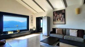Un soggiorno moderno con un'ampia finestra, un divano, un tavolino da caffè e un quadro appeso al muro.