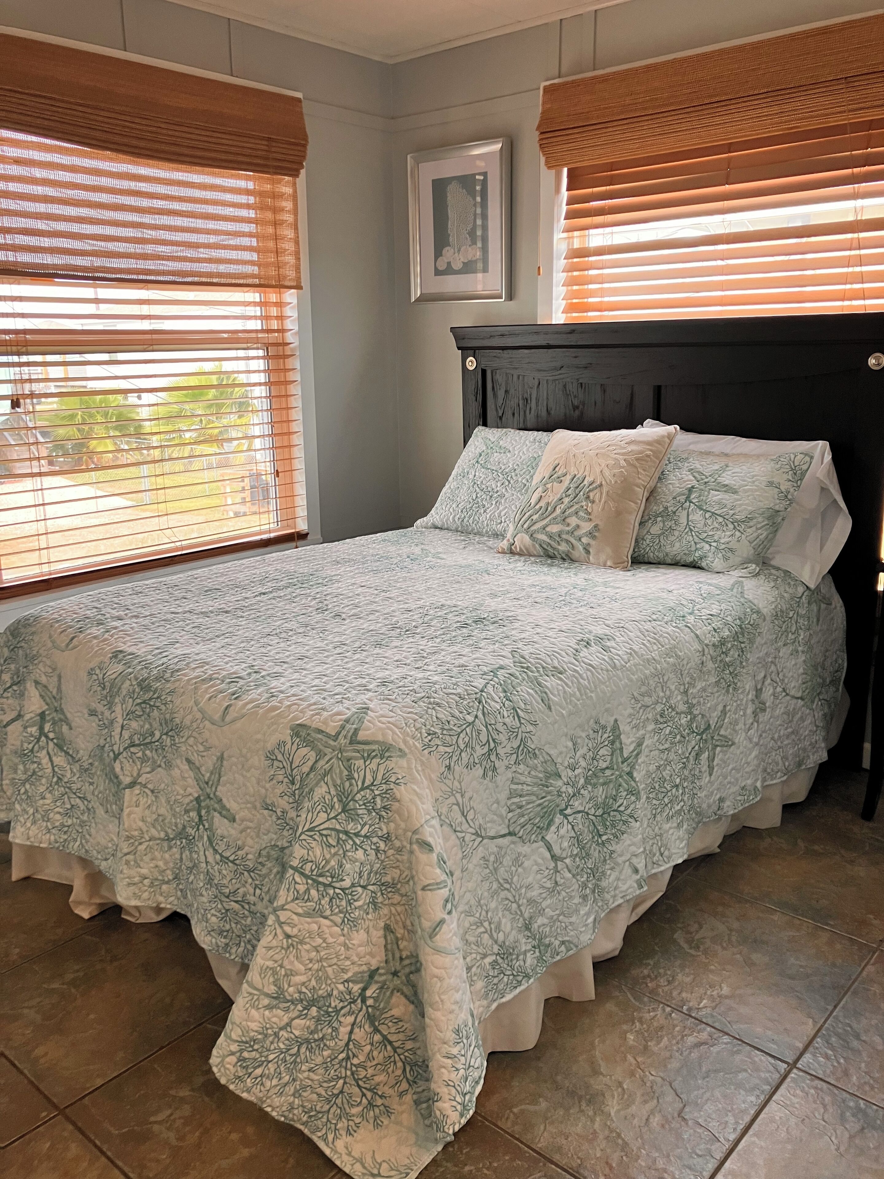 A bedroom with a bed, a headboard, and a window with blinds.