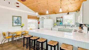 Une cuisine moderne dotée d’un grand îlot central, de tabourets de bar et d’un plafond en bois.