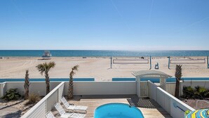 Uitzicht op het strand vanaf een balkon, met een zwembad, ligbedden en een reddepost.