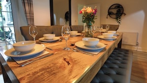 A dining table set with white bowls, wine glasses, and cutlery, with a vase of flowers in the center.