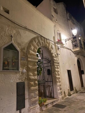 A historic building with a large arched entrance, a small window with a cross, and a balcony with plants. - A CASA DI BARBARA Comfort and relax in the Heart of Galatina (Galatina)