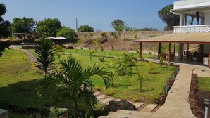 A landscaped garden with a pathway leading to a covered seating area. - Beautiful double room with pool and kitchen, 850m to the Indian Ocean (Diani Beach)