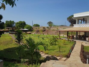 Un jardín ajardinado con un sendero que lleva a una zona de estar cubierta.