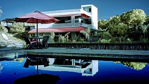 A modern building with a pool, outdoor furniture, and a reflection in the water. - Beautiful double room with pool and kitchen, 850m to the Indian Ocean (Diani Beach)