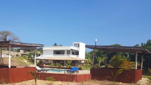 A modern house with a pool, covered seating areas, and a view of the surrounding landscape. - Beautiful double room with pool and kitchen, 850m to the Indian Ocean (Diani Beach)