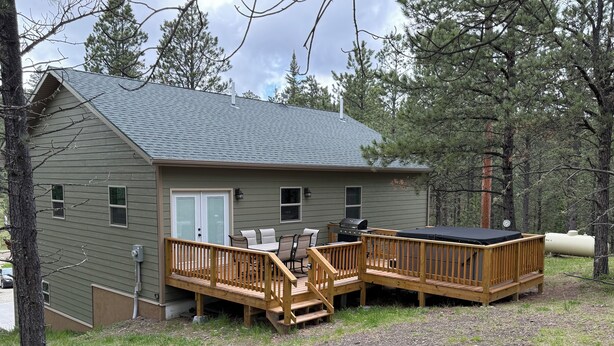 A cabin with a deck, a grill, and a water tank. - Mile-high Pines Lodge (South Lawrence)