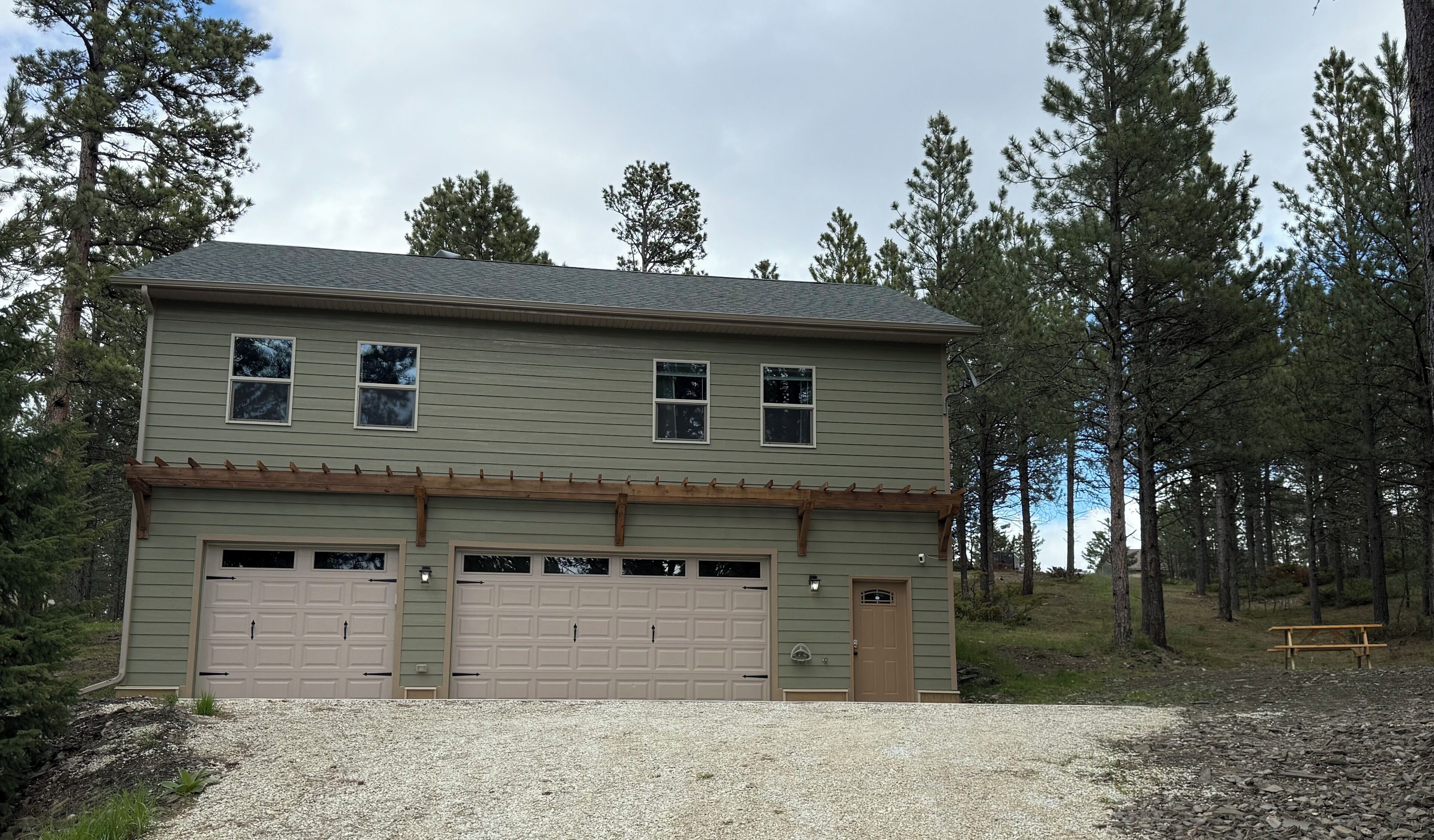 A two-story house with a garage, surrounded by trees.