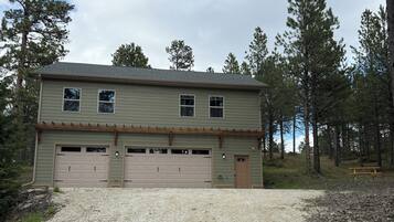 A two-story house with a garage, surrounded by trees.