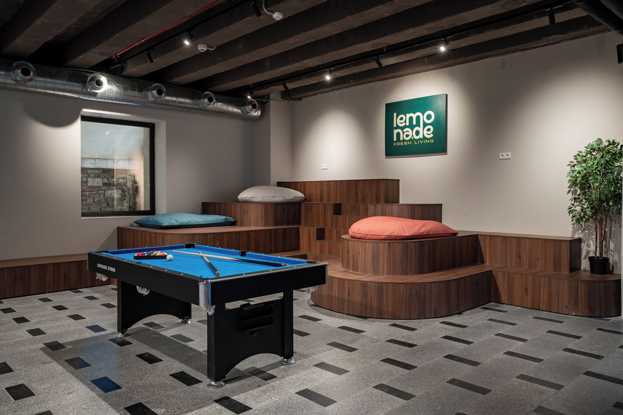 Une table de billard dans une pièce avec un banc en bois, un panneau fixé au mur et une plante en pot.