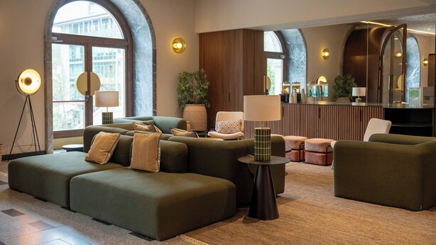 Un moderno vestíbulo de hotel con un sofá modular, una pequeña mesa redonda y un espejo grande.