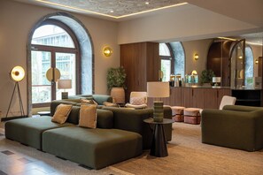 Un moderno vestíbulo de hotel con un sofá modular, una pequeña mesa redonda y un espejo grande.