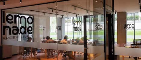 Un espacio de oficina moderno con paredes de vidrio, múltiples estaciones de trabajo y el logo 'lemoade FRESH LIVING' en el vidrio.