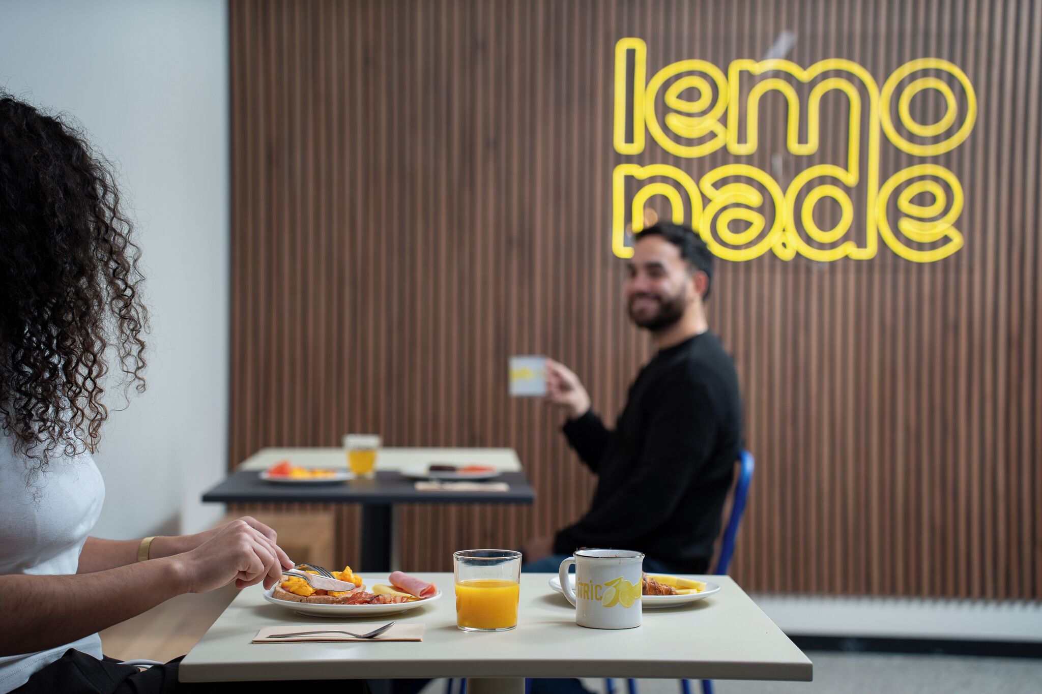 A breakfast setting with a table, plates of food, a glass of orange juice, and a coffee mug.