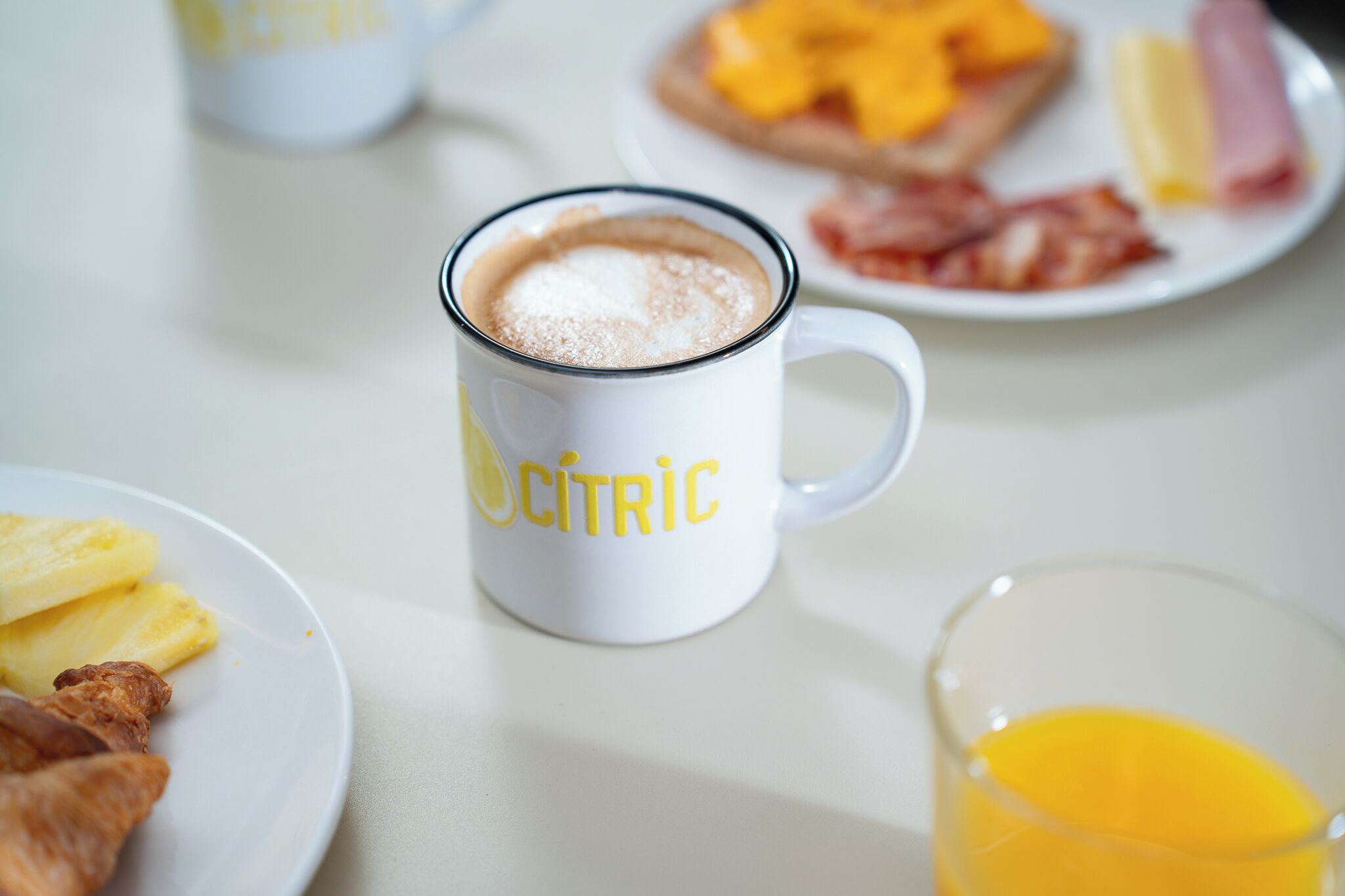 Een ontbijtsetting met een koffiemok met de tekst 'CITRIC', borden met eten waaronder toast en eieren, en een glas sinaasappelsap.