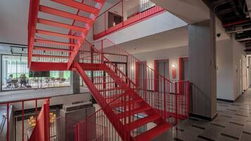 Un intérieur moderne, agrémenté d’un imposant escalier en colimaçon rouge qui relie plusieurs étages.