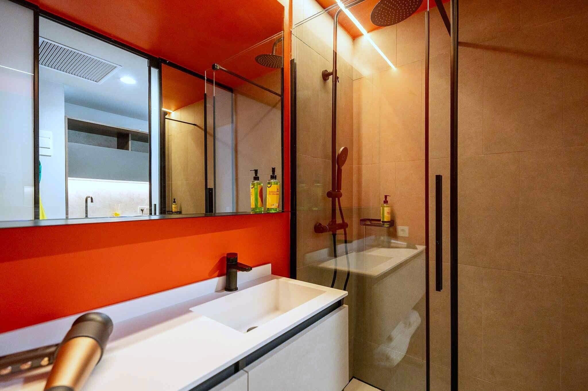 A modern bathroom with a glass shower enclosure, a white sink, and a large mirror.