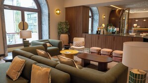 Un moderno vestíbulo de hotel con un sofá verde, una mesa de centro redonda y una recepción.