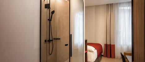 A modern bathroom with a glass-enclosed shower, a visible toilet, and a separate sink area.
