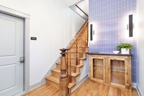 Una escalera de madera con una puerta blanca que indica el número 101 y una pared con azulejos azules.