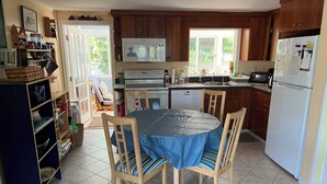 A kitchen with wooden cabinets, a microwave, a refrigerator, and a dining table with chairs.