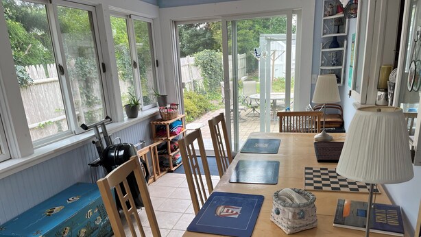 A sunlit room with a wooden table, chairs, and a bench.