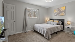 A bedroom with a bed, a nightstand, a lamp, a TV, and a window with curtains. - Family-Friendly w/ Hot Tub | 12 min to Broadmoor (Colorado Springs)