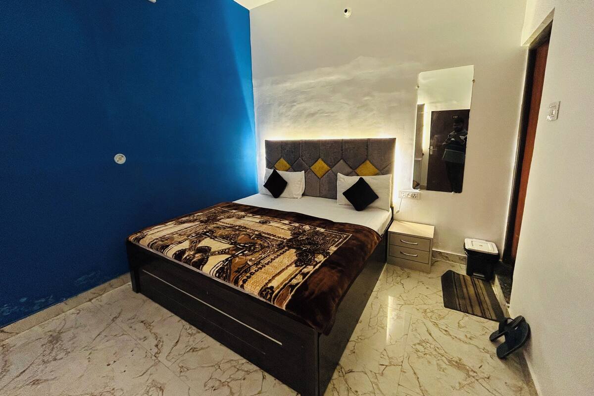 Une chambre à coucher avec un lit, une table de chevet, un miroir et un mur d’accent bleu.