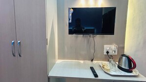 A modern kitchenette with a built-in TV, a kettle, and a tray with cups. - Divya Darshan Stay (Faizabad)