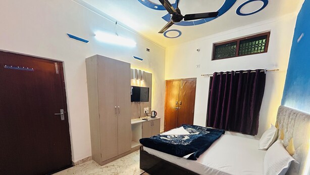 A bedroom with a bed, wardrobe, mirror, and ceiling fan. - Divya Darshan Stay (Faizabad)