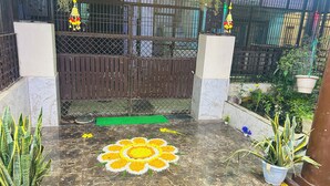 A gated entrance with a marble floor, potted plants, and a decorative flower pattern. - Divya Darshan Stay (Faizabad)