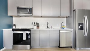Una cucina moderna con elettrodomestici in acciaio inossidabile, tra cui microonde, forno, lavastoviglie e frigorifero.