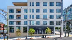 Un edificio a più piani dal design architettonico moderno, con un'ampia vetrata all'ingresso e una segnaletica che indica “GSBE Apartments”.