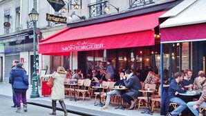 Un café al aire libre con toldos rojos y mesas en la terraza.