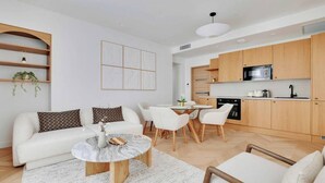 Una sala de estar moderna con un sofá blanco, una mesa de centro de mármol y un comedor con sillas blancas.