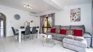 A modern living room with a grey sofa, a dining table with chairs, and a glass coffee table. - Salicos Benagil Pool Villa (Lagoa)