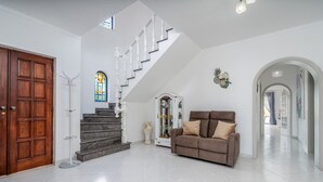 A spacious living area with a staircase, a wooden door, a sofa, and a decorative mirror. - Salicos Benagil Pool Villa (Lagoa)