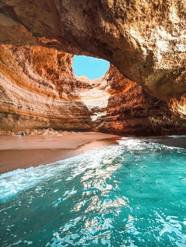 A natural rock formation with a cave opening to a beach and clear turquoise water. - Salicos Benagil Pool Villa (Lagoa)