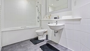 Un bagno moderno con vasca, water, lavabo e specchio.