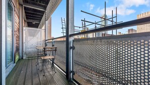A balcony with a wooden floor, metal railing, and a perforated metal partition. - 1 Bed Apartment Sleeps 5 - Balcony - Wifi & Tv (Birmingham)