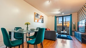 A modern living room with a dining area, featuring a glass table, teal chairs, and a grey sofa. - 1 Bed Apartment Sleeps 5 - Balcony - Wifi & Tv (Birmingham)