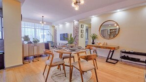 A modern dining area with a round table, wooden chairs, and a central plant.