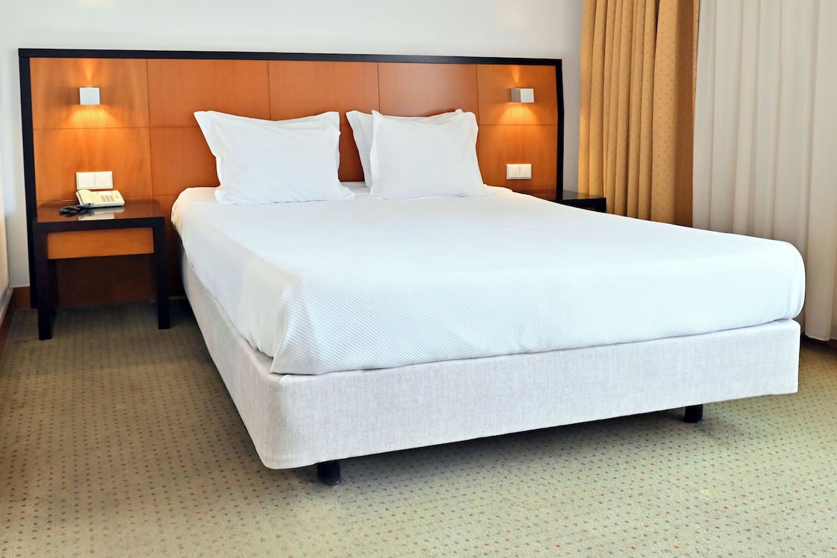 A hotel room with a large bed, two bedside tables with lamps, and a window with curtains.