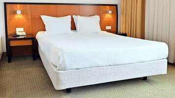 Una habitación de hotel con una cama grande, dos mesitas de noche con lámparas y una ventana con cortinas.