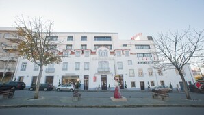 Un immeuble avec un restaurant au rez-de-chaussée, de nombreuses fenêtres et une statue devant.