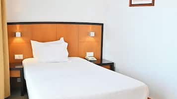 Ein Hotelzimmer mit einem großen Bett, zwei Nachttischen mit Lampen, einem Telefon und einem gerahmten Bild an der Wand.