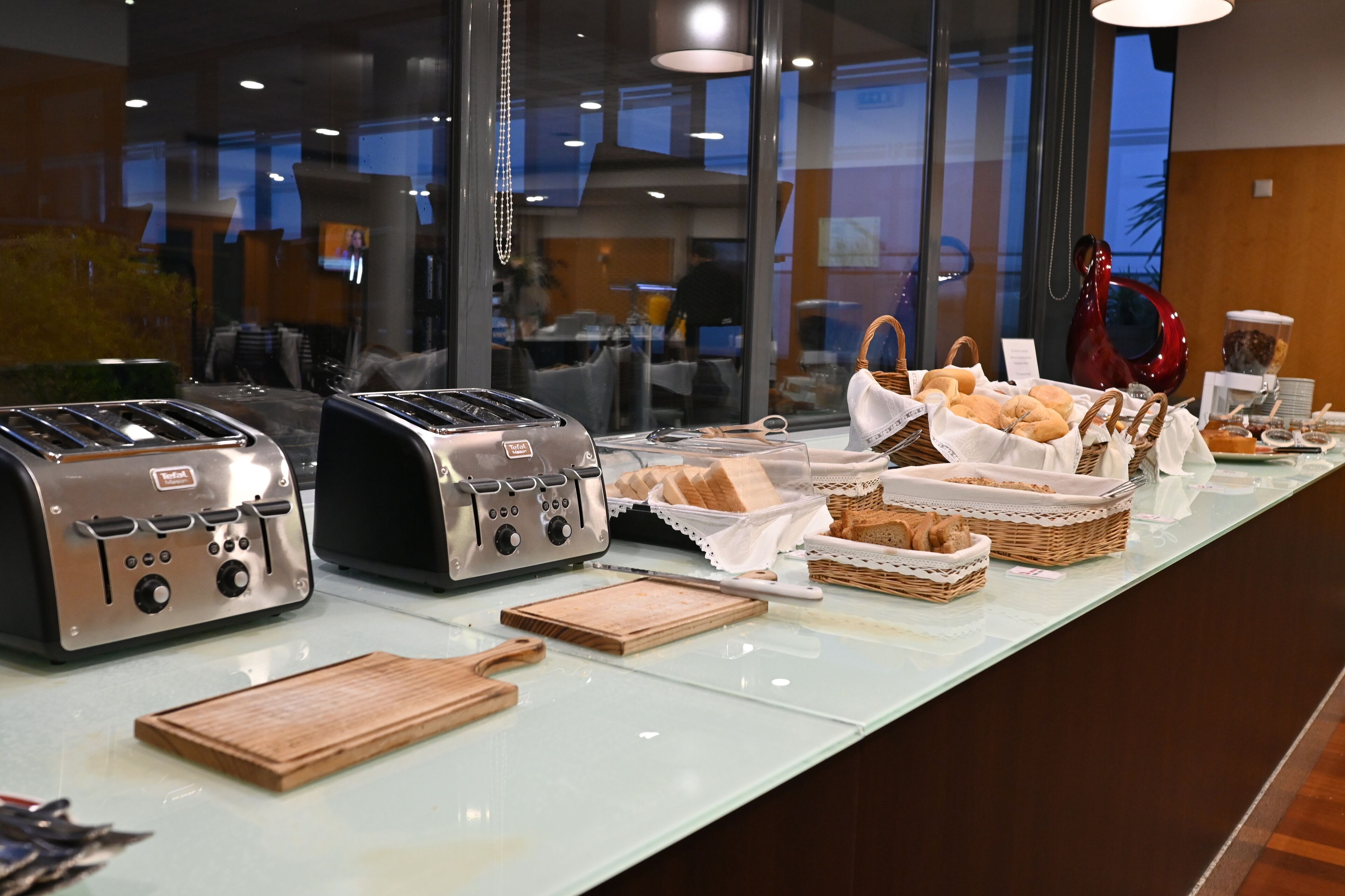 Een ontbijtbuffet met diverse broden en gebak, twee broodroosters en een koffieapparaat.