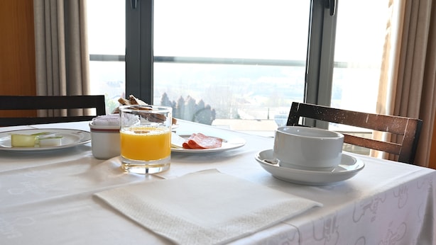 Une table de petit-déjeuner avec un verre de jus d’orange, une assiette de nourriture et une tasse de café.