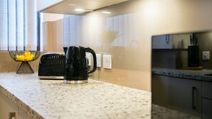 A kitchen with a granite countertop, a black electric kettle, and a fruit bowl. - Craigievar Crescent Apartment | Grampian Lettings (Aberdeen)