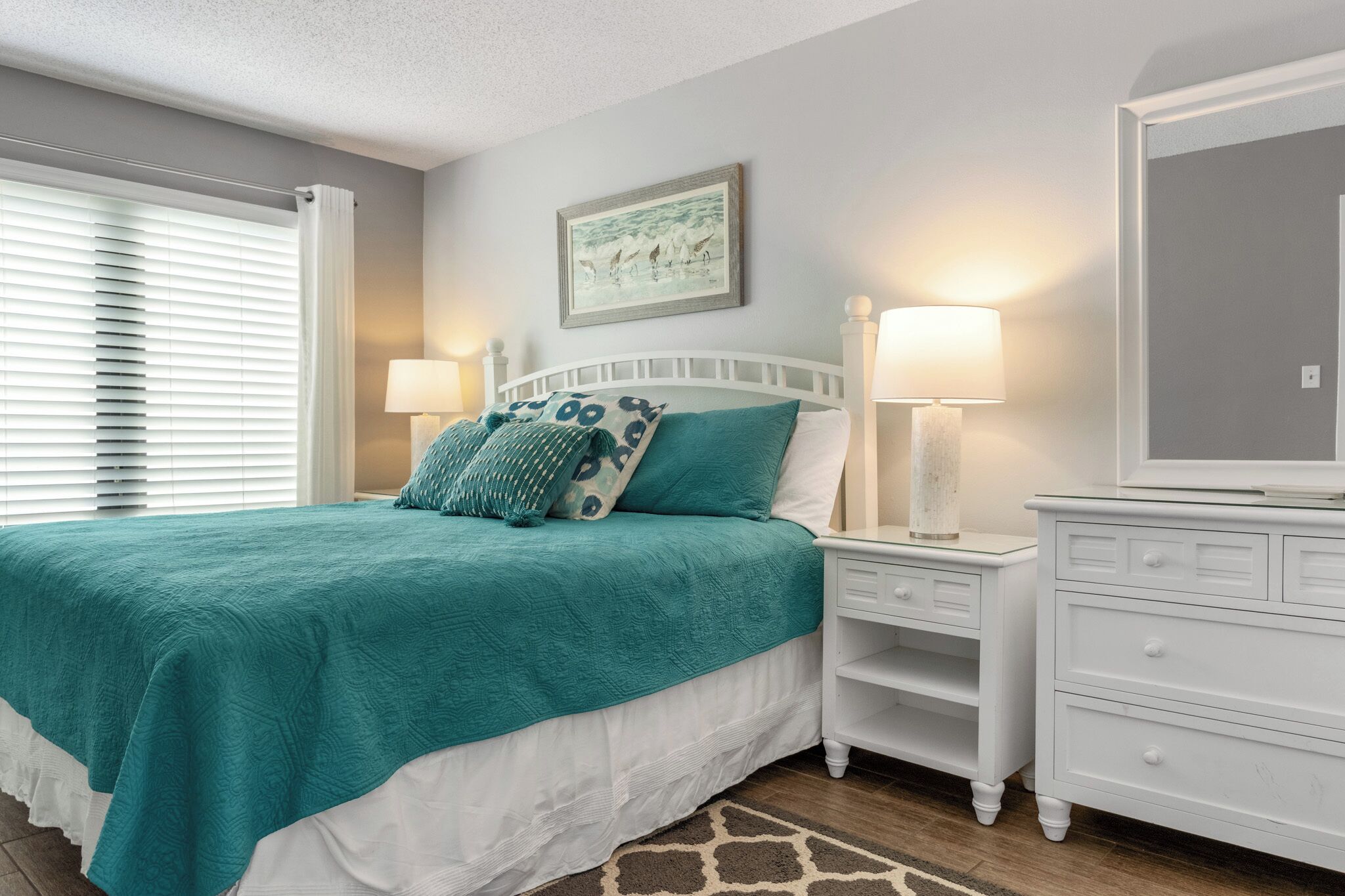 A bedroom with a bed, two bedside tables, a nightstand, a dresser, and a wall-mounted TV.
